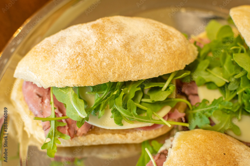 Prosciutto Italian sandwich with arugula and provolone cheese - top view Prosciutto Italian sandwich with arugula and provolone cheese - top view