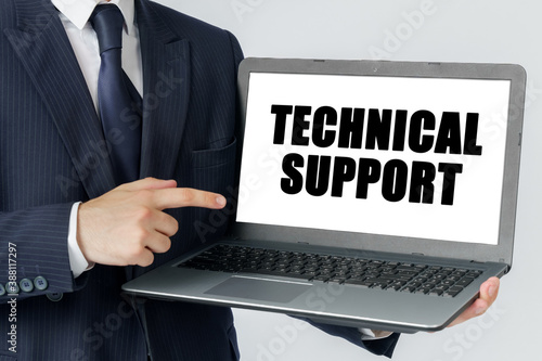 A businessman holds a laptop in his hands and shows on the screen with the text - TECHNICAL SUPPORT