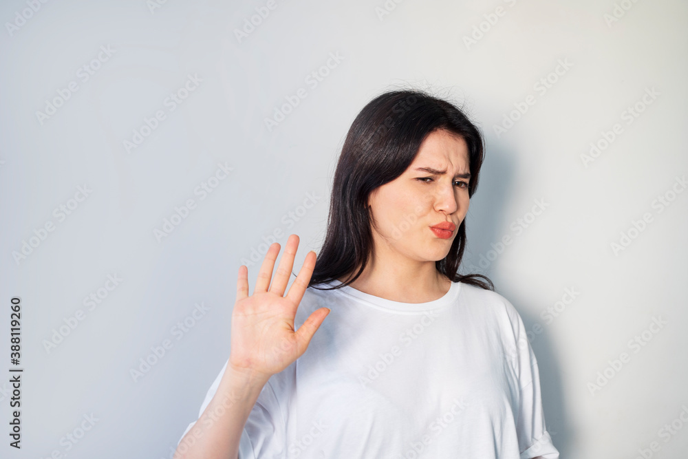 dissatisfied woman pushing with the back of her hand on gray background dissatisfied woman pushing with the back of her hand on gray background