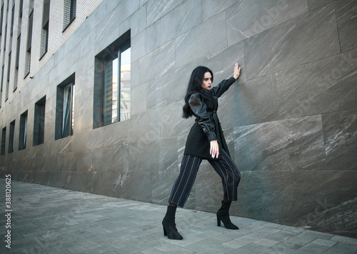 Girl in fashionable black casual clothes on background of stone wall  modern urban architecture  vogue style photo