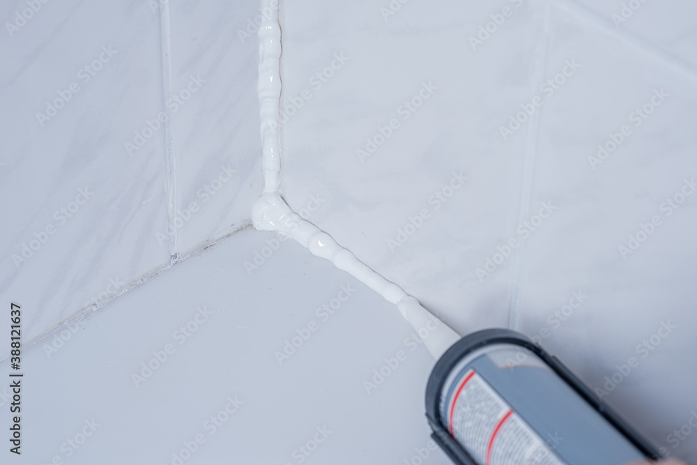 Plumber Applying silicone sealant to the tile joint