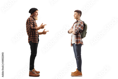 Full length profile shot of a bearded young man standing and talking to a teenage male student