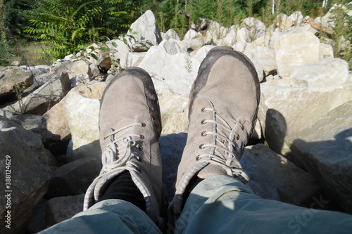 Neutrale graue Barfußschuhe in der Sonne vor sandigem grauen Steinen . Outdooraktivitäten für die Füße . Fußansicht . Bird Perspective on Foot perspective . bare foot shoes in matching environment .