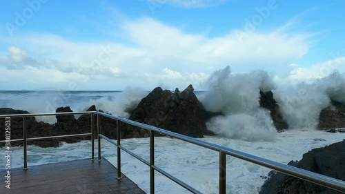 Big waves crashing against the rocks and splashing foam several meters up
