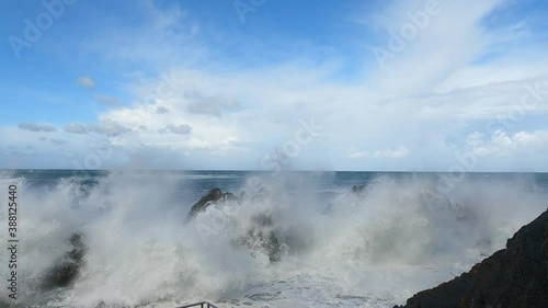 Big waves crashing against the rocks and splashing foam several meters up