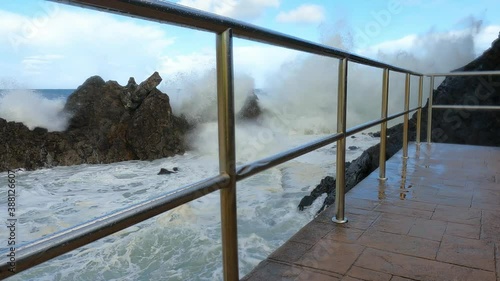 Big waves crashing against the rocks and splashing foam several meters up