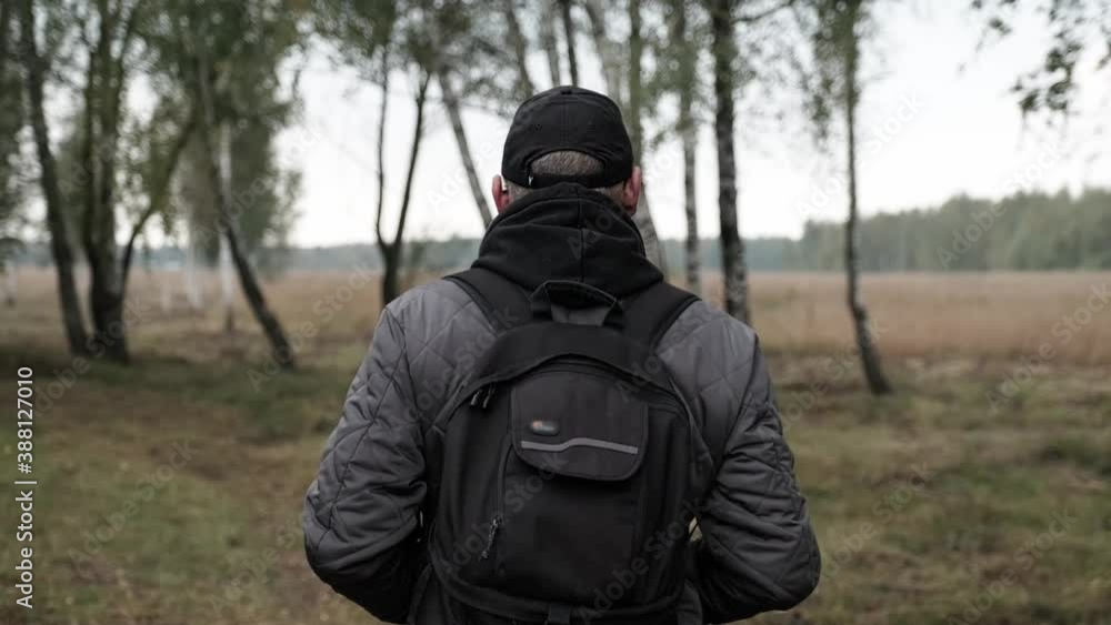 A man with knapsack walks in the amazing autumn forest. Adult man with backpack in fall forest nature. A man with knapsack walks in the amazing autumn forest. Adult man with backpack in fall forest nature.