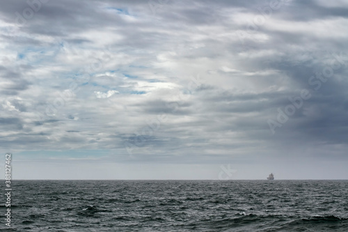 Cloudy seascape with a ship on the horizon