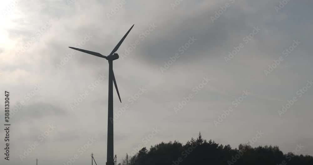 silhouette of rotating blades of a windmill propeller on gray sky background. Wind power generation. Pure green energy. silhouette of rotating blades of a windmill propeller on gray sky background. Wind power generation. Pure green energy.