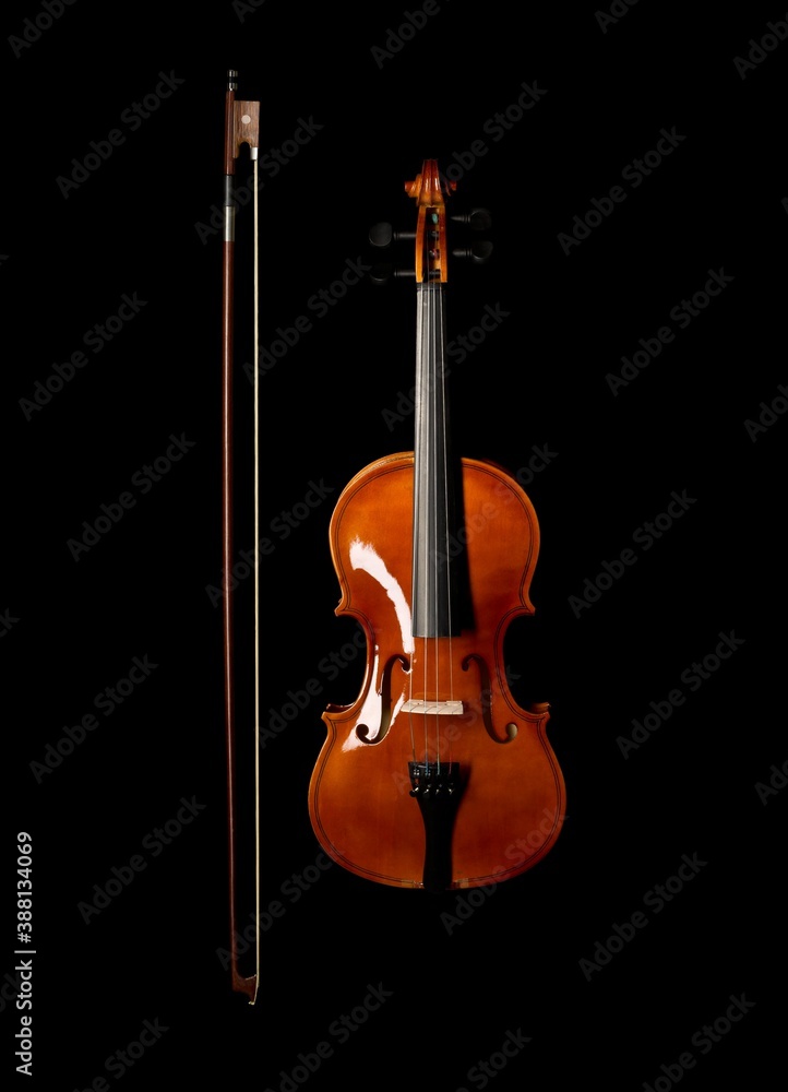 Brown wooden fiddle or violin, classic musical instrument, with bow next to it isolated on black background, flat lay top view from above Brown wooden fiddle or violin, classic musical instrument, with bow next to it isolated on black background, flat lay top view from above