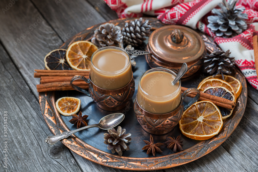 Copper cups of hot coffee with cream, with cinnamon, anise on a copper tray and a wooden background. Copper cups of hot coffee with cream, with cinnamon, anise on a copper tray and a wooden background.