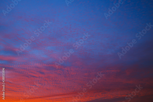 Blue sky and red broken clouds background. © angeldibilio