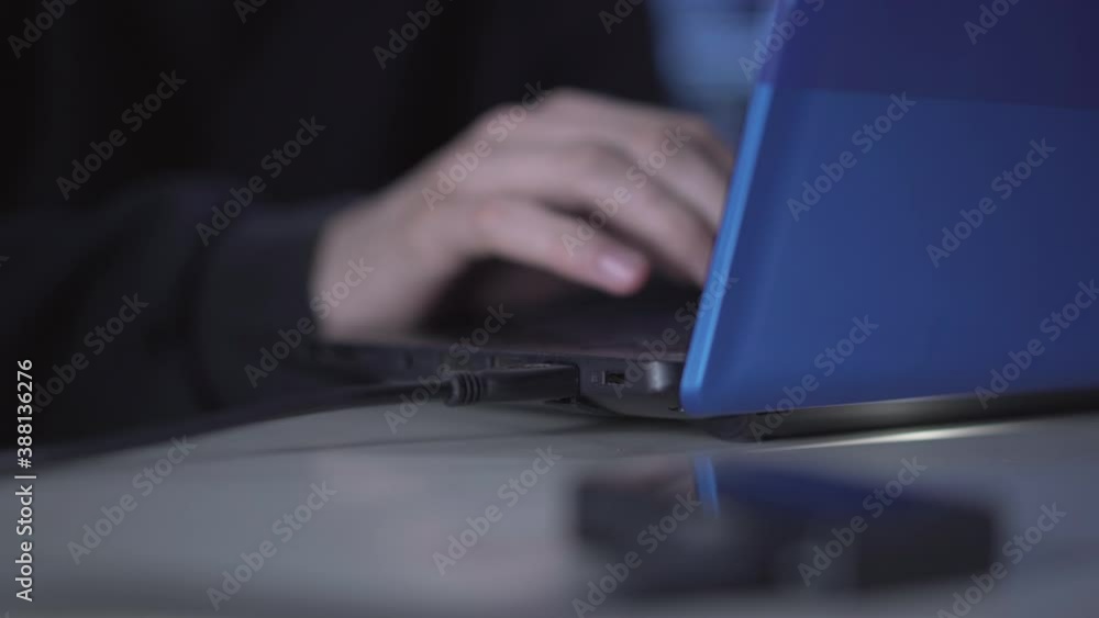 Unrecognizable man plugging in USB device into laptop. Male hand inserting connector in port and typing on keyboard. Young professional hacker hacking online password or stealing data. Unrecognizable man plugging in USB device into laptop. Male hand inserting connector in port and typing on keyboard. Young professional hacker hacking online password or stealing data.
