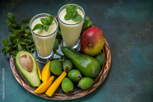 Two glasses of fruit smoothie made from mango, avocado, feijoa and cream on a tray