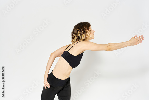 Slender woman in leggings on a light background doing fitness gymnastics exercises