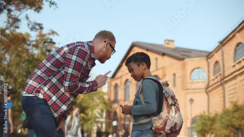Side view of young male teacher scolding naughty african student outdoors photo