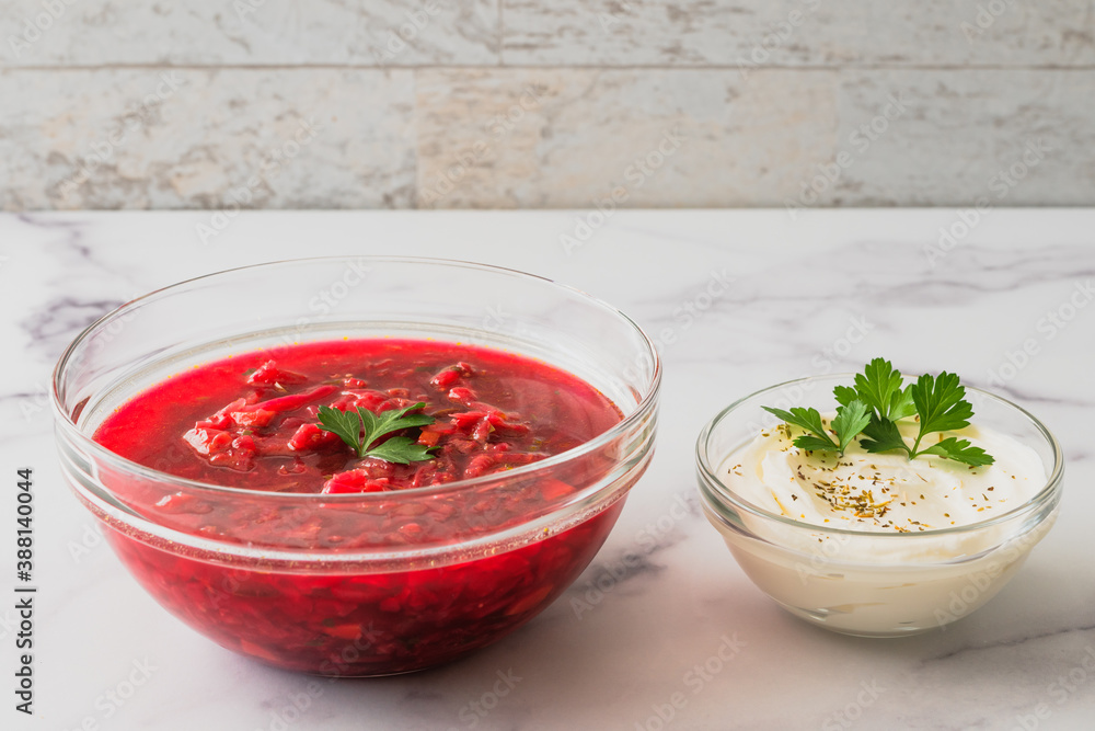 Beet soup and sour cream with fresh cilantro close up in a glass bowls on marble background Beet soup and sour cream with fresh cilantro close up in a glass bowls on marble background