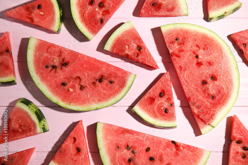Slices of ripe watermelon on pink wooden table, flat lay