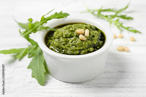 Bowl of tasty pesto and arugula on white wooden table