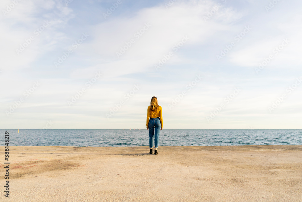 Young woman standing by sea against sky Young woman standing by sea against sky