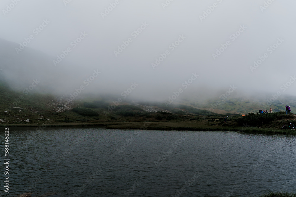 Mountain lake full of fog in rainy day. Windy and storm weather in the karpathian mountains