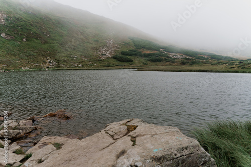 Big lake and rocks in foggy day. Fog in Karpathian mountains. Tourism in Ukraine. Freedom and unity with nature