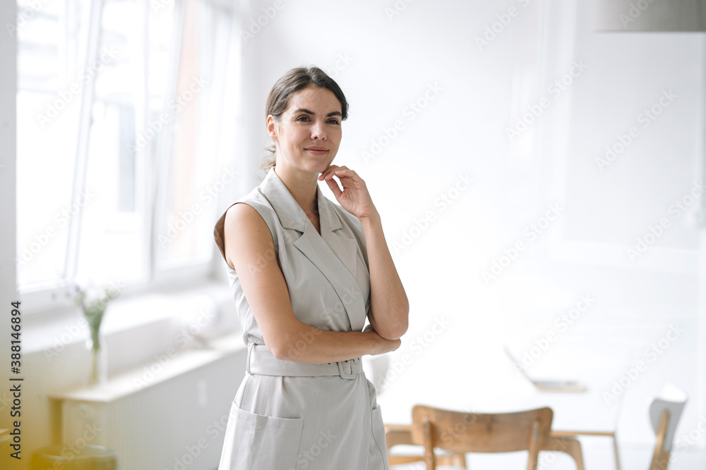 Beautiful businesswoman with hand on chin standing at office Beautiful businesswoman with hand on chin standing at office