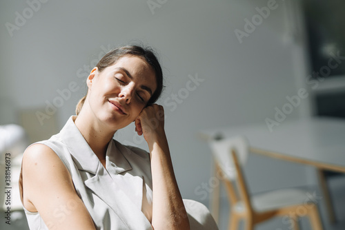 Woman with head in hands day dreaming while sitting on chair at office photo