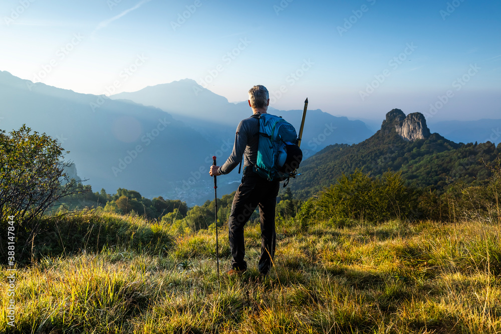 Male hiker with backpack looking at mountain against sky during sunrise, Orobie, Lecco, Italy Male hiker with backpack looking at mountain against sky during sunrise, Orobie, Lecco, Italy