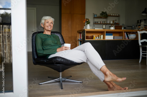 Senior woman looking away while holding coffee cup at home