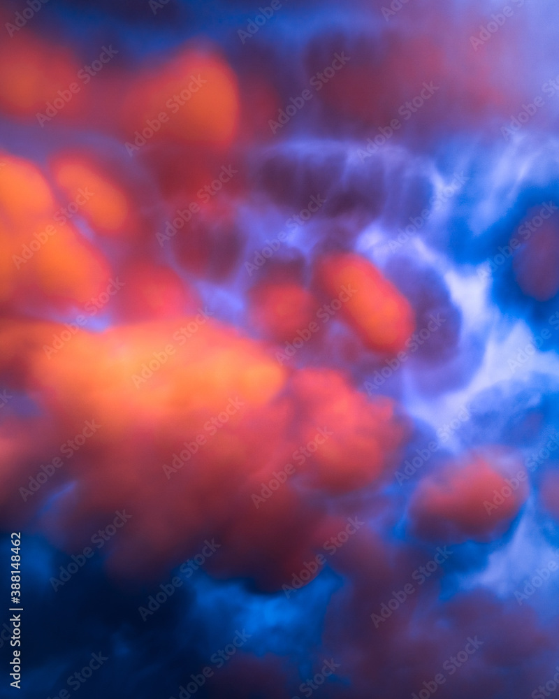 Obraz premium Red and orange clouds at sunset or sunrise with very curious shapes. Mammatus clouds. Strange and artistic sky clouds vertical background.