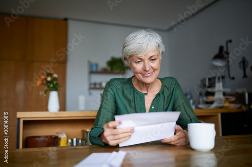 Senior woman reading letter while sitting at home photo