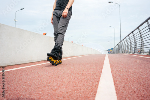 Legs of young man inline skating on bridge against sky in city photo