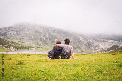 Romatinc picture of a young couple in the mountains lying in the grass in a foggy day. Travel and explore freedom © miranda