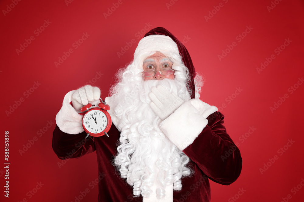 Santa Claus holding alarm clock on red background. Christmas countdown Santa Claus holding alarm clock on red background. Christmas countdown