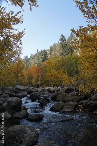 Scenic landscape view of trees with golden fall colors framing a river with large boulders 