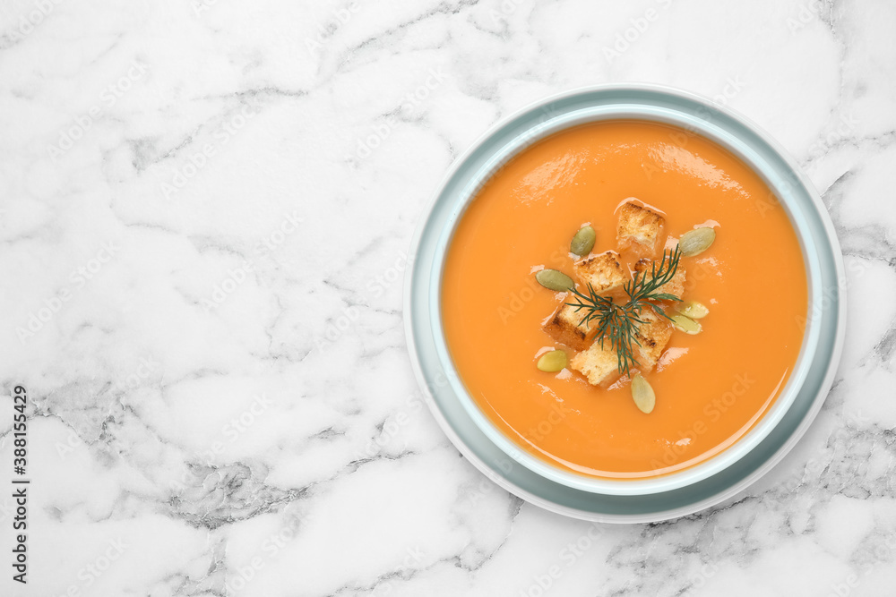 Tasty creamy pumpkin soup with croutons, seeds and dill in bowl on white marble table, top view. Space for text Tasty creamy pumpkin soup with croutons, seeds and dill in bowl on white marble table, top view. Space for text