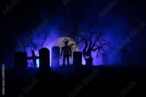 Scary view of zombies at cemetery dead tree, moon, church and spooky cloudy sky with fog, Horror Halloween concept with glowing pumpkin. Selective focus © zef art