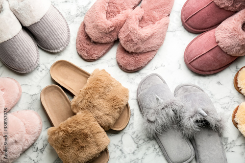 Many different soft slippers on white marble background, flat lay photo