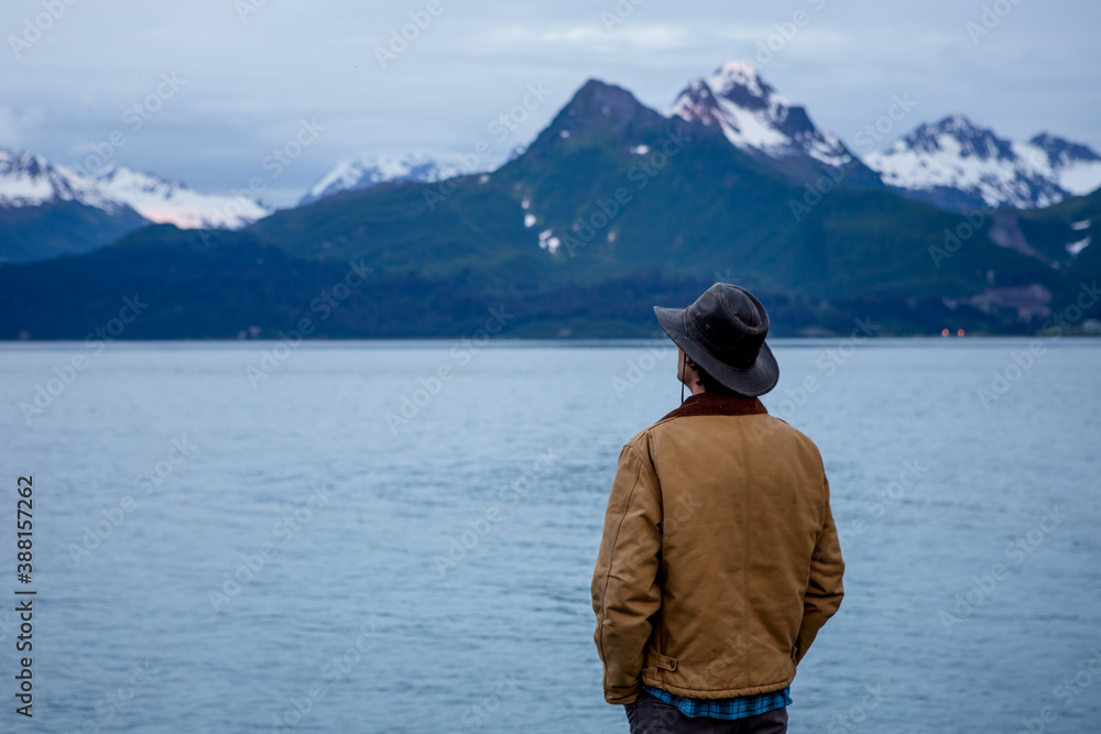 Man Standing Seaside with Mountain Backdrop Man Standing Seaside with Mountain Backdrop