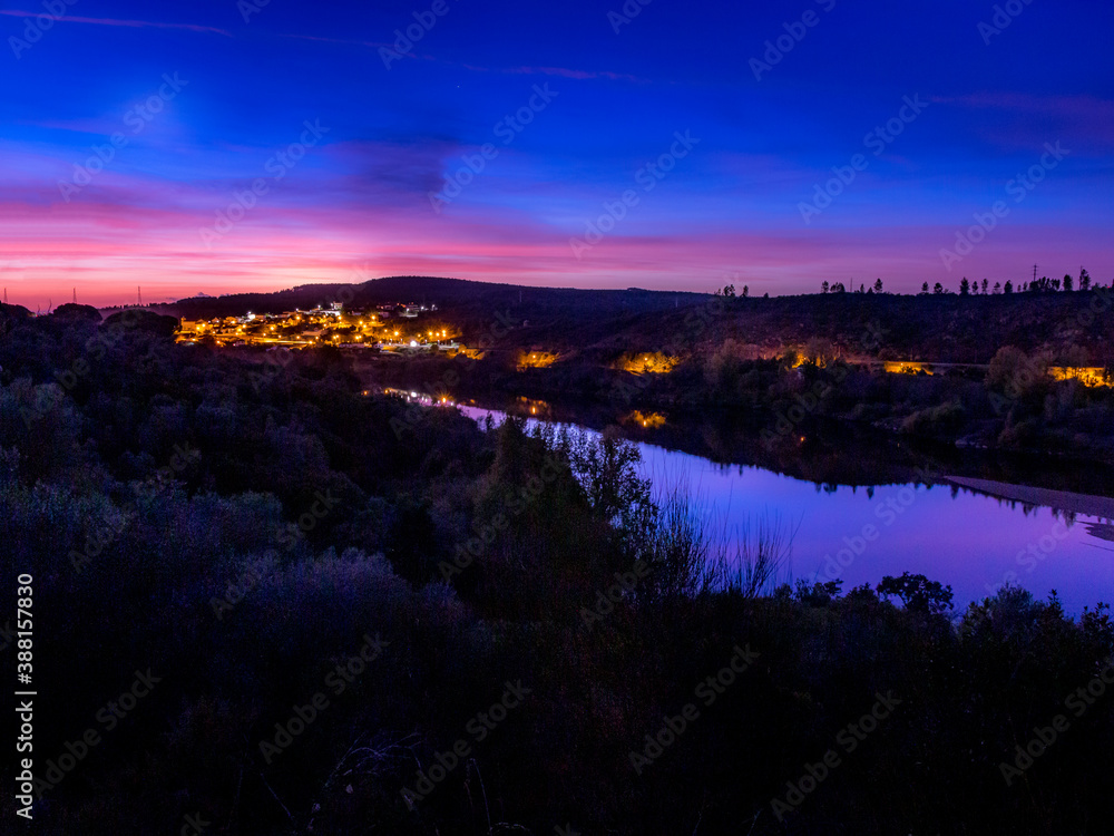 Autumn sunset from a hill top with a village and river on the horizon