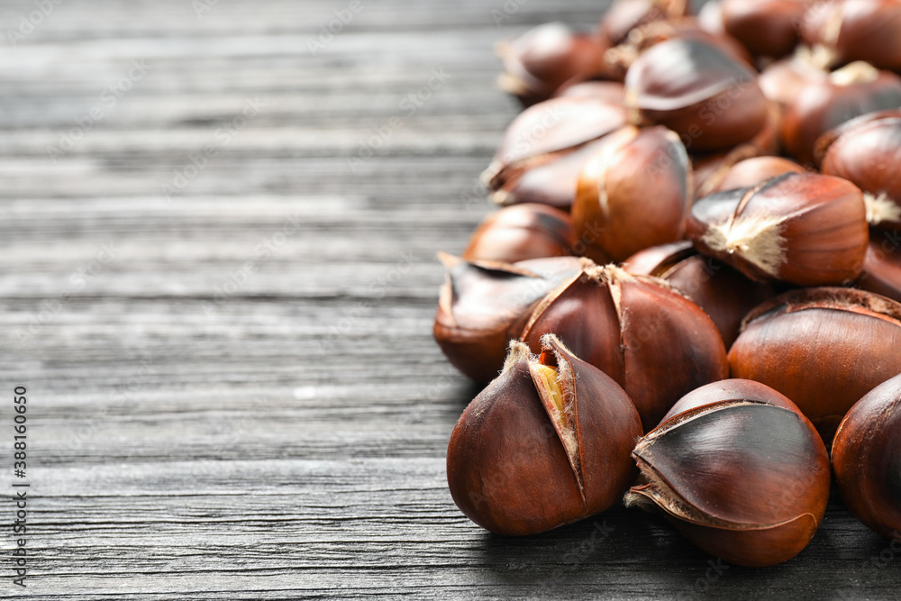 Delicious roasted edible chestnuts on black wooden table, closeup. Space for text Delicious roasted edible chestnuts on black wooden table, closeup. Space for text