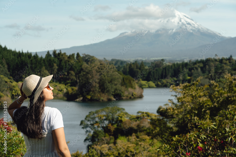 Lady looking at Mount Taranaki with lake and forest landscape. New Zealand landscape