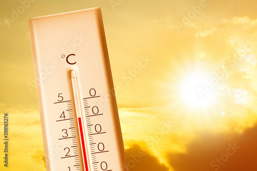 Weather thermometer showing high temperature and sunny sky with clouds on background