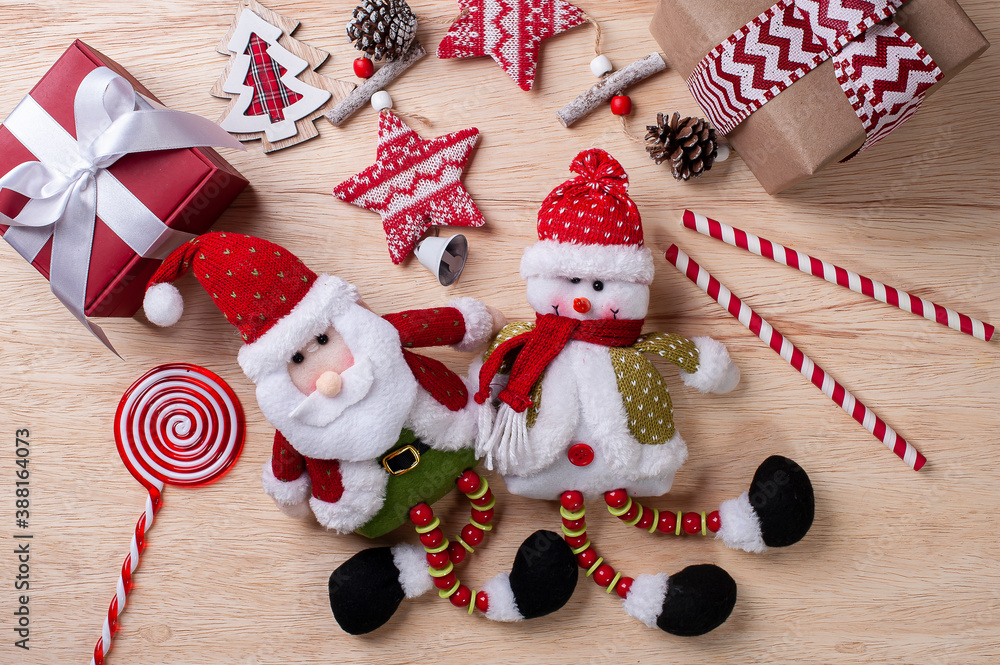 Obraz premium Christmas composition on wooden background with ribbons and gifts, Santa Claus and snowman. Top view.