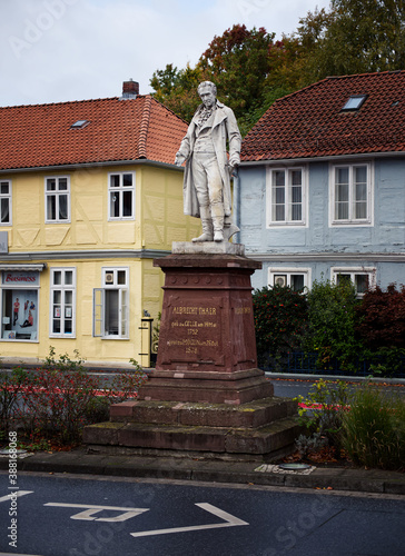 A statue of Albrecht Thaer with two old buildings in the background on a street photo