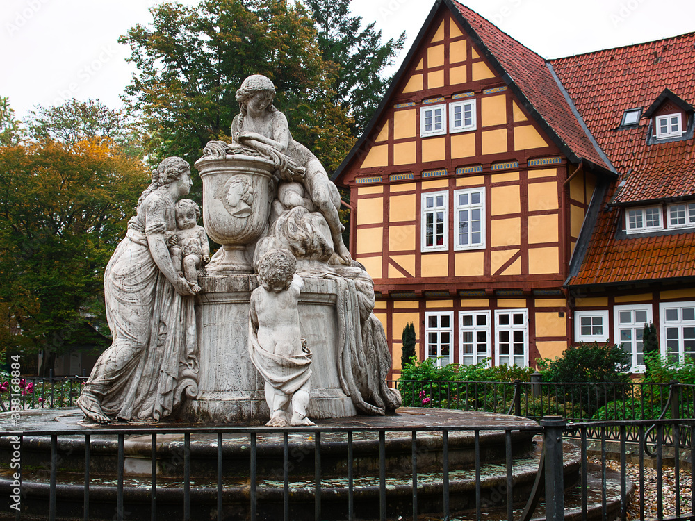 An old historical fountain in front of a half-timbered house