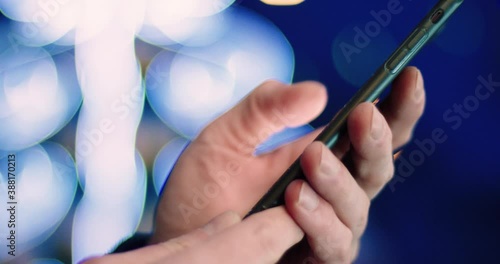 Close up of man holding smartphone in his hands and flipping through news feed, scroll finger on screen while standing on the outside. photo