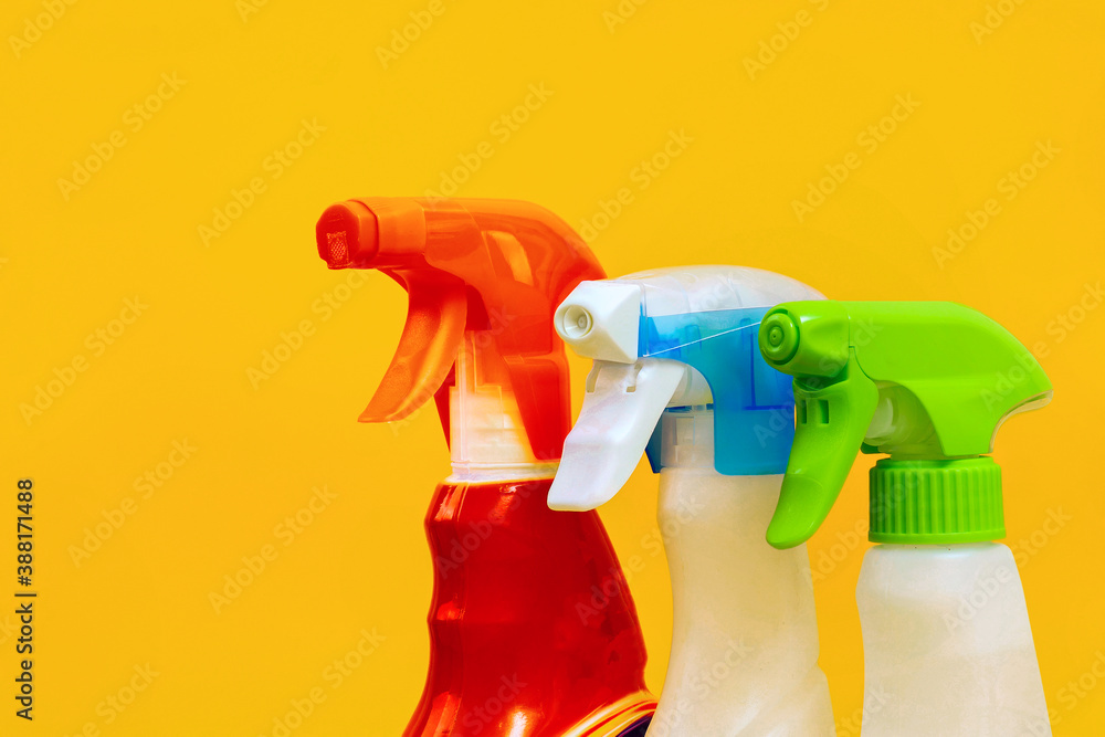 three different spray bottles on yellow background in a row