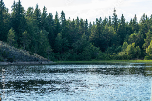 beautiful landscape with green, natural trees and plants, rocks on the island, natural pond, lake against the blue sky in Karelia, Russia